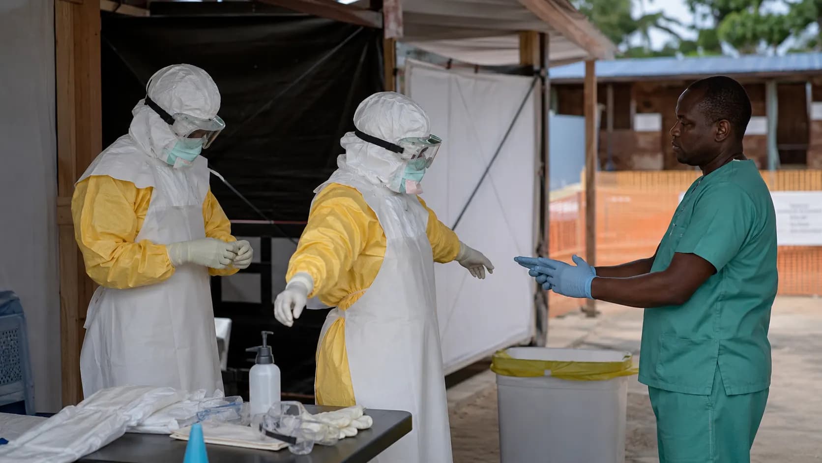 Healthcare workers checking protective equipment before entering an Ebola treatment area.