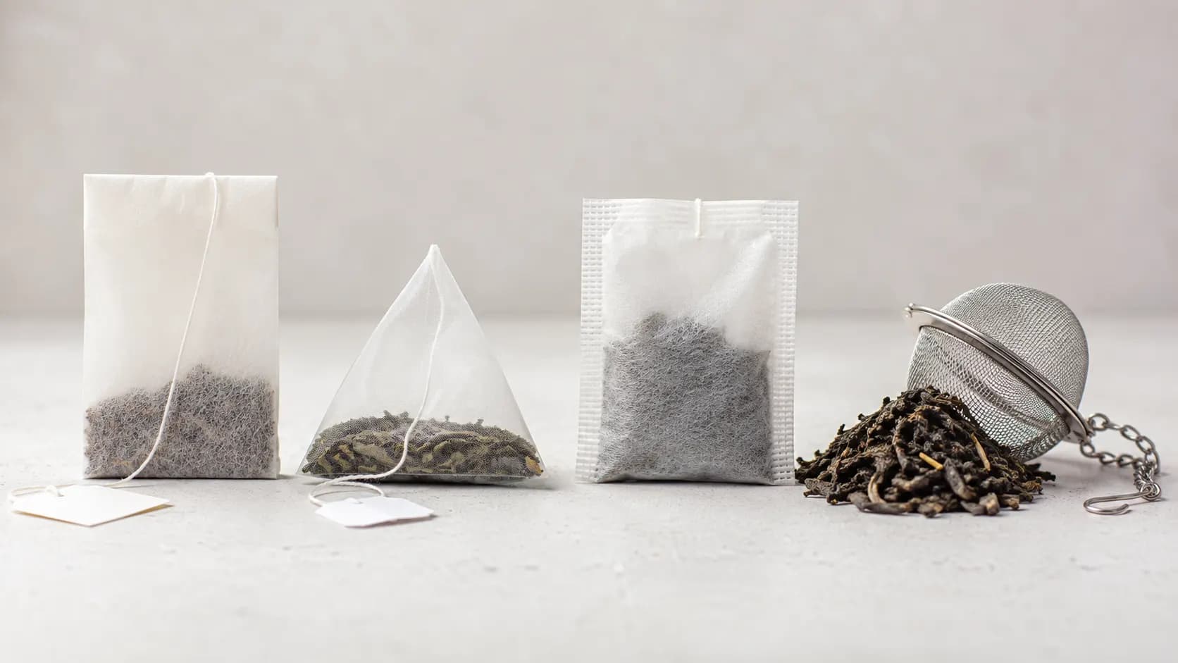 Several different tea-bag styles beside loose tea and a stainless-steel infuser.