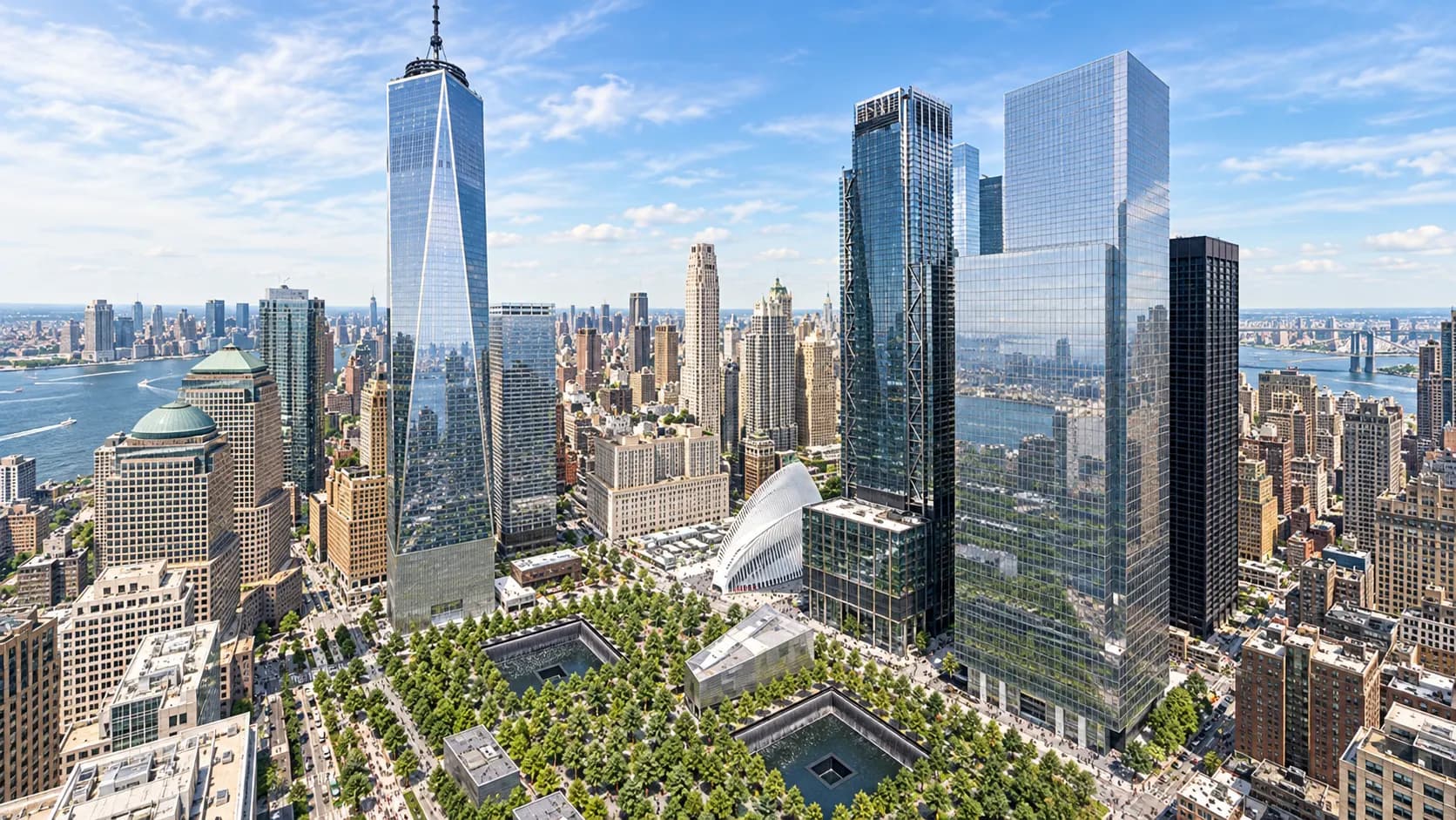 An aerial view of the World Trade Center campus showing One World Trade Center beside the two 9/11 Memorial pools.